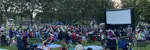 Large outdoor movie screen with people watching in a park