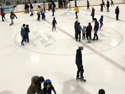 Group of adults and children skating on indoor rink
