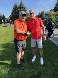 Two man standing on a green lawn and shaking hands