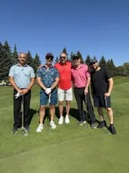 Five men on a golf course, four holding golf clubs