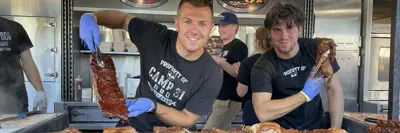 Cooks holding ribs and meat at ribfest food booth