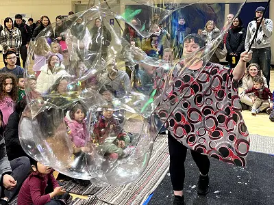 Woman performing bubble show with families watching