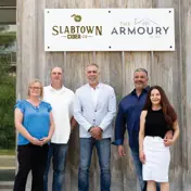 Mayor Mrakas (centre) with Lori and Jason Feddema (left), and Marco and Laura Cassano (right), of Slabtown, standing under a Slabtown and Armoury sign