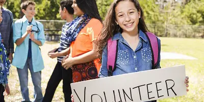 Teen girl holding sign with word volunteer