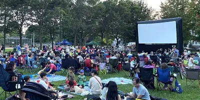 Large outdoor movie screen with people watching in a park