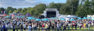 Wide view of four ribfest stage with large group of attendees at event