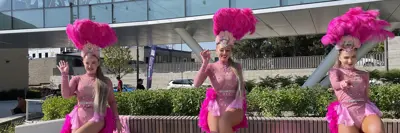 Three female dancers in pink flamingo outfits on stage