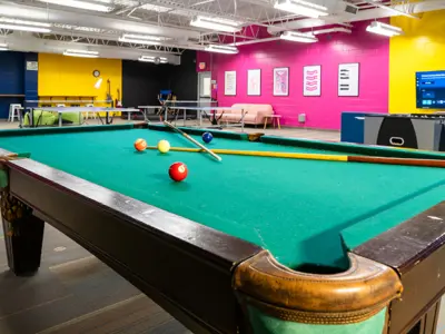Green covered pool table with sport equipment