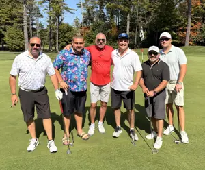 Six men on a golf course, five holding golf clubs