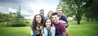Group of teens huddling together in park during fall season