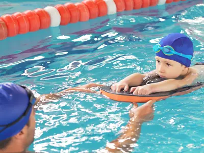 Swim instructor teaching boy to swim in pool